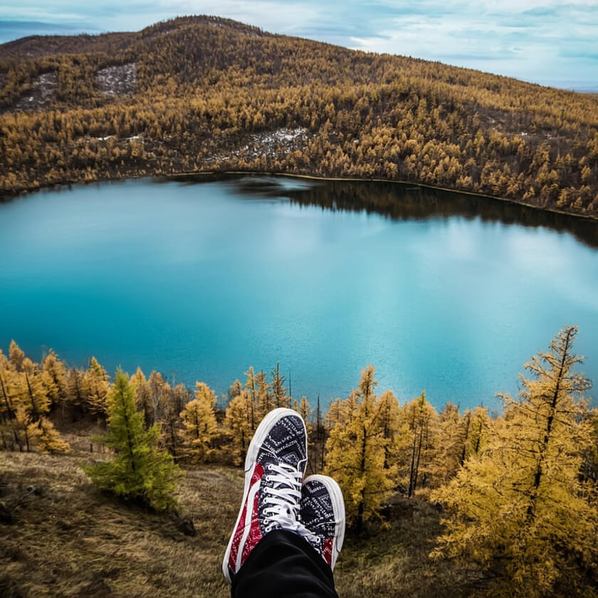 Just someone's feet as they are  sitting overlooking a lake in mountains